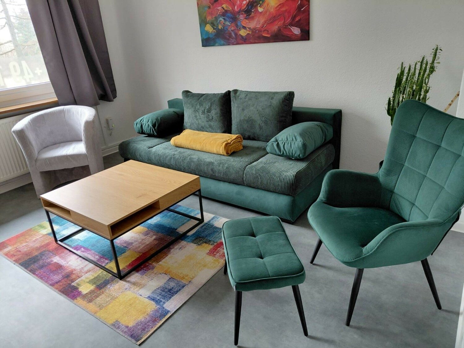 Wohnzimmer mit grünem Sofa, Sessel und Couchtisch